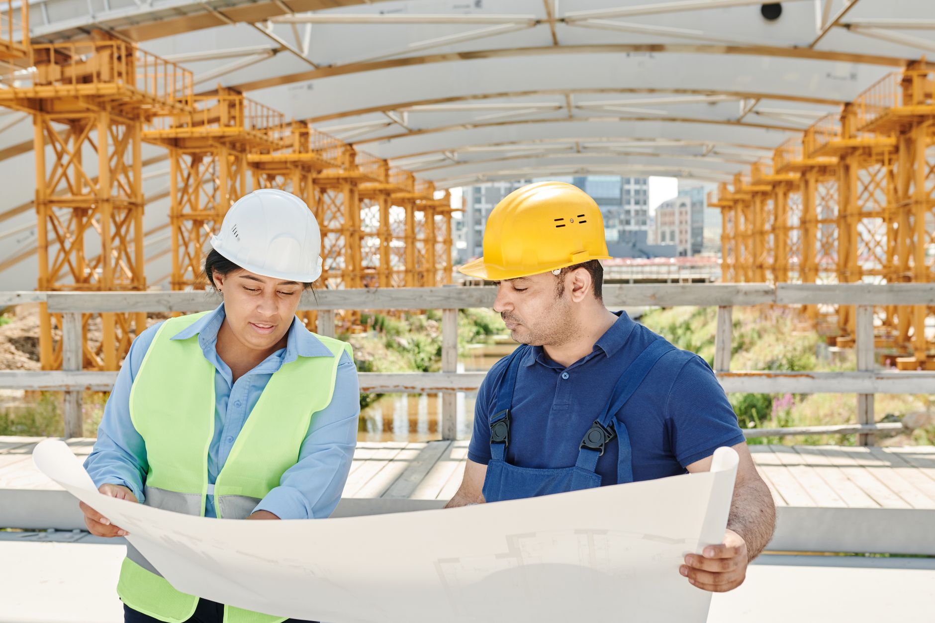 Site engineers reviewing drawings by a concrete column